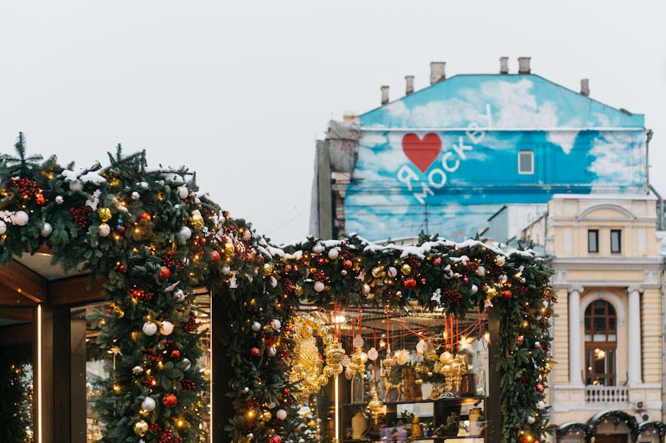 Illuminated Christmas decorations and festive archways on a Moscow street at twilight with snow-dusted buildings