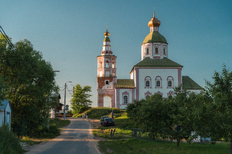Historic white Orthodox church with blue onion dome rising above grassy fields in Suzdal, Russia under a clear sky