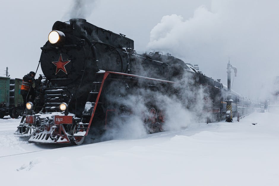 Classic steam locomotive moving through a snow-covered Siberian landscape with evergreen trees in the distance