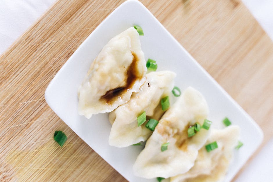 Traditional Russian pelmeni dumplings served with sour cream on a wooden plate