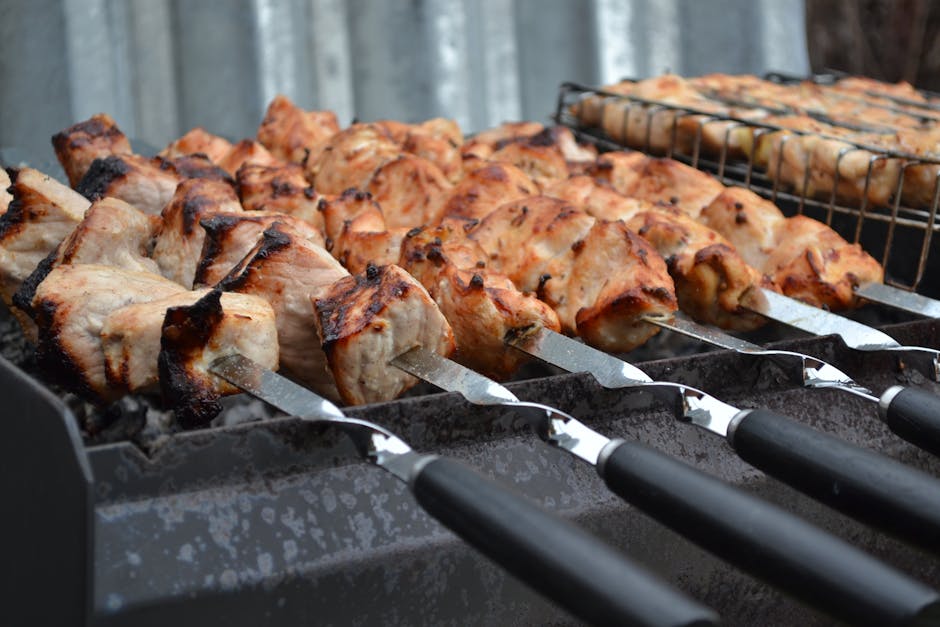 Grilled shashlik meat skewers with charred edges served with fresh herbs