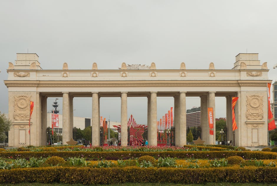 The Triumphal Gate entrance to Gorky Park in Moscow with colorful flags and walking paths on a bright day