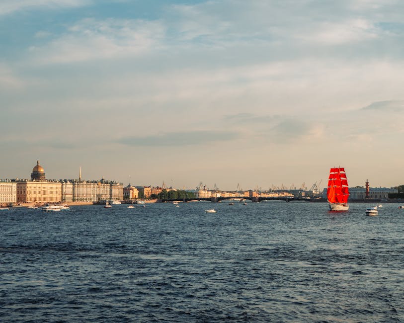 Panoramic view of the Neva River with a tall ship displaying scarlet red sails passing historic Saint Petersburg architecture